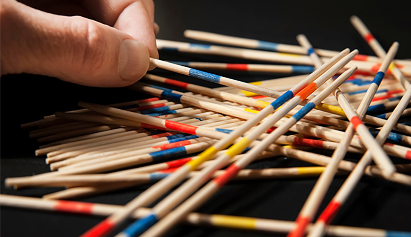 Hand grabbing small sticks on table