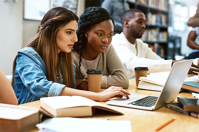 Two young women working on a project together in a library