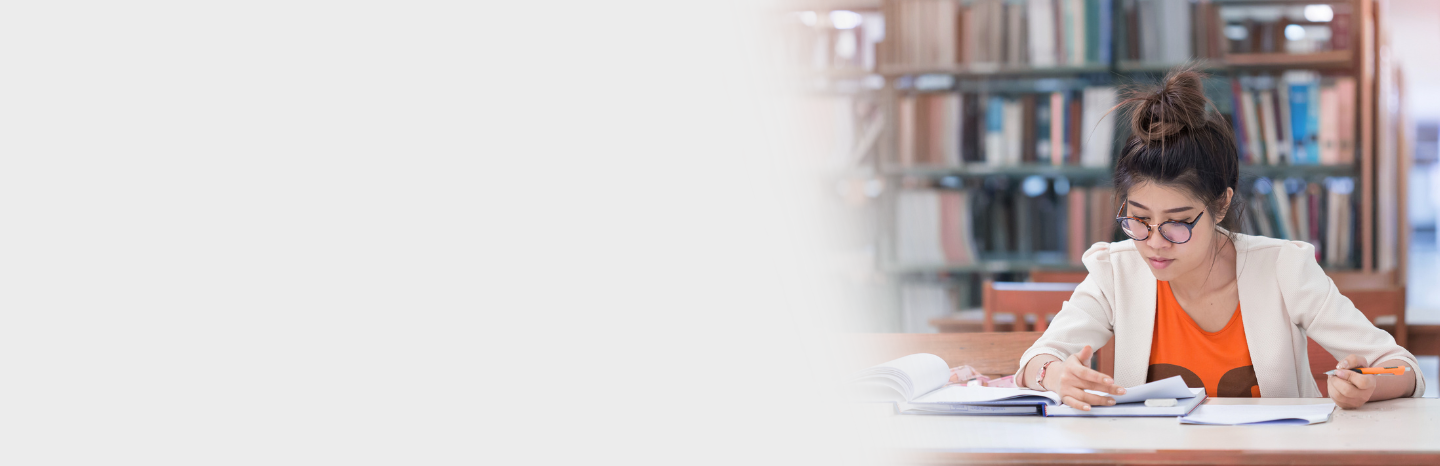 female student studying and writing in library