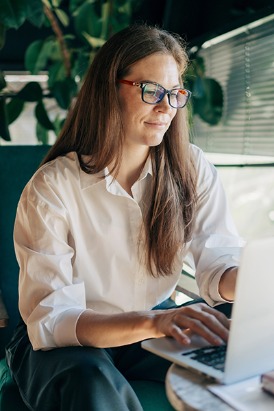 Young woman sitting at a table typing on a laptop