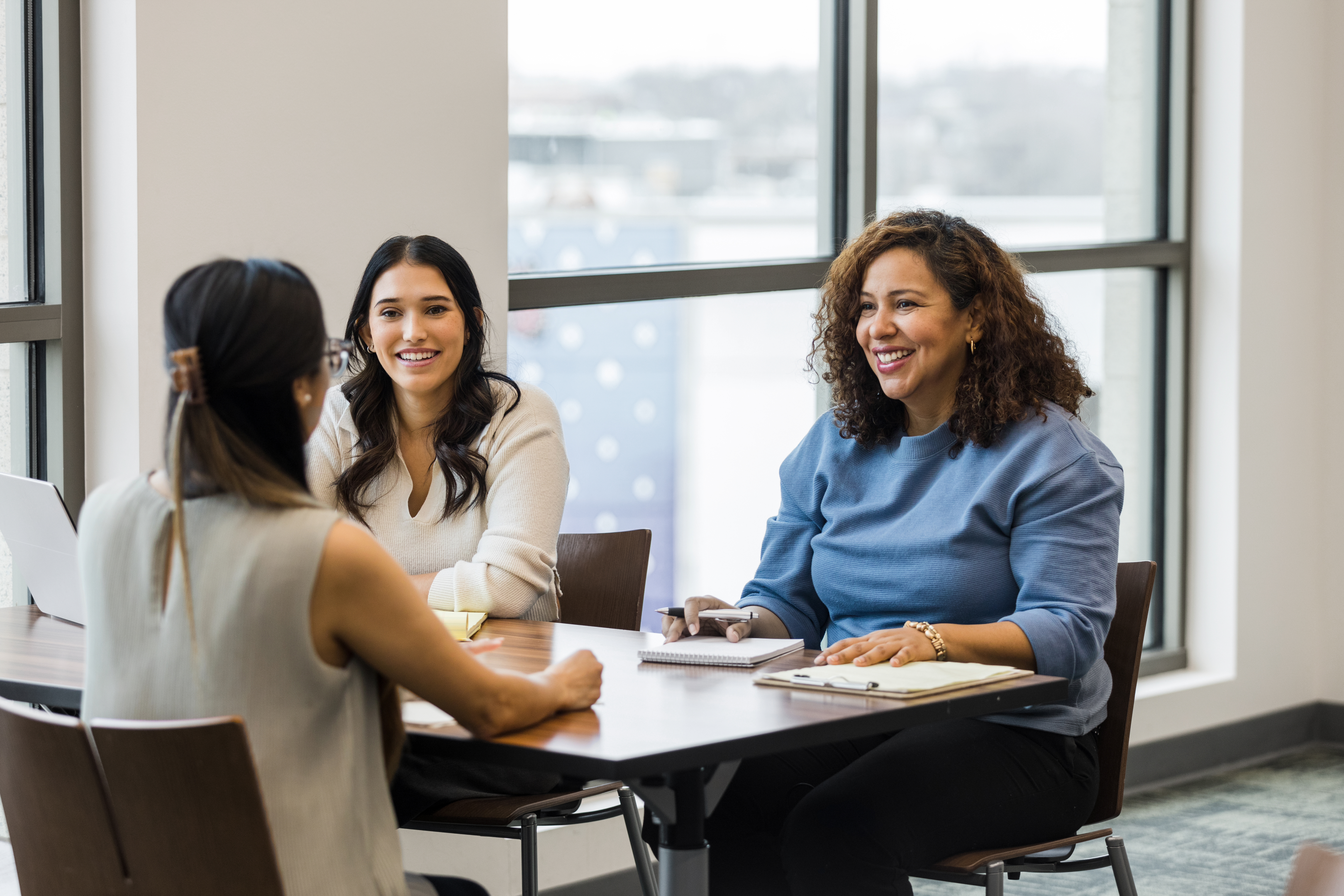 The businesswomen meet with their marketing team lead to review their business strategy going into the new quarter.
