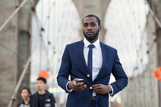 Man in a business suit walking outside in New York on a bridge