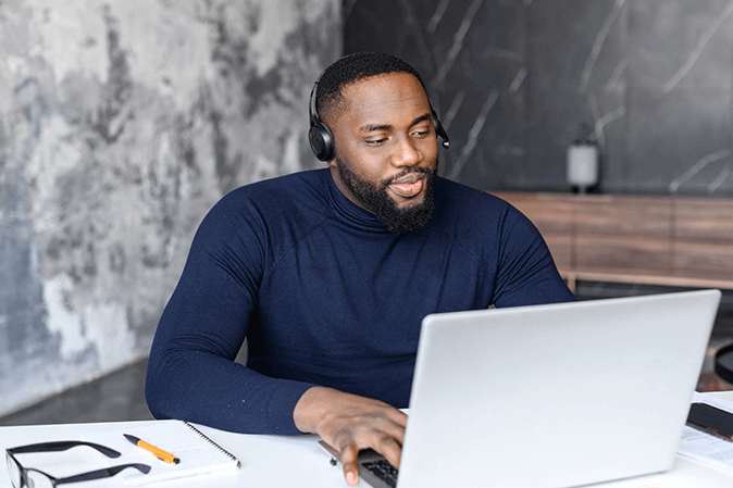 Young man wearing headphones while typing on a laptop