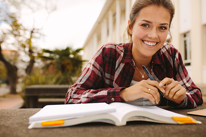 Young woman smiling outside with an open book