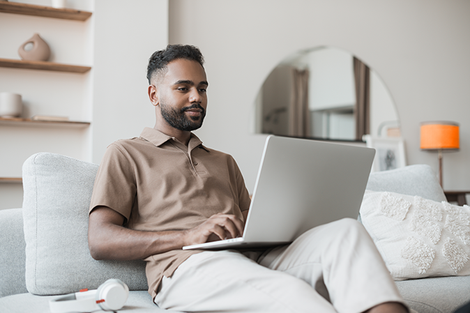 Handsome young man using laptop computer at home. Student men resting in his room. Home work or study, freelance, online learning and casual business concept