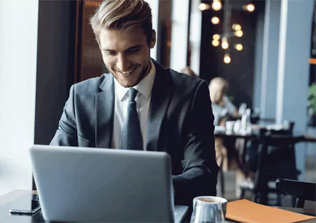 Young professional working on a laptop while seated at a table in a café