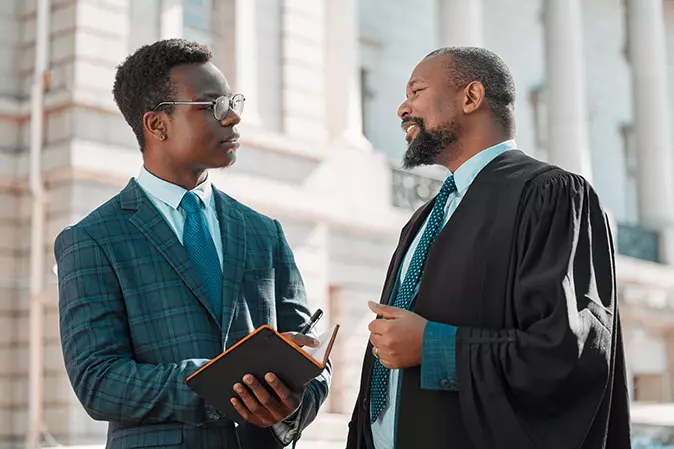 Lawyer taking notes while speaking with a judge outside a courthouse