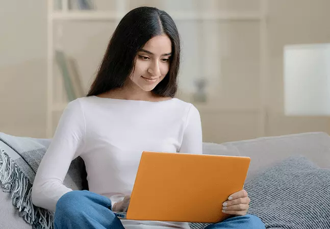 Young woman studying on a laptop while seated on a couch at home