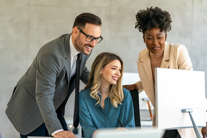 Man working with two women on a computer in an office