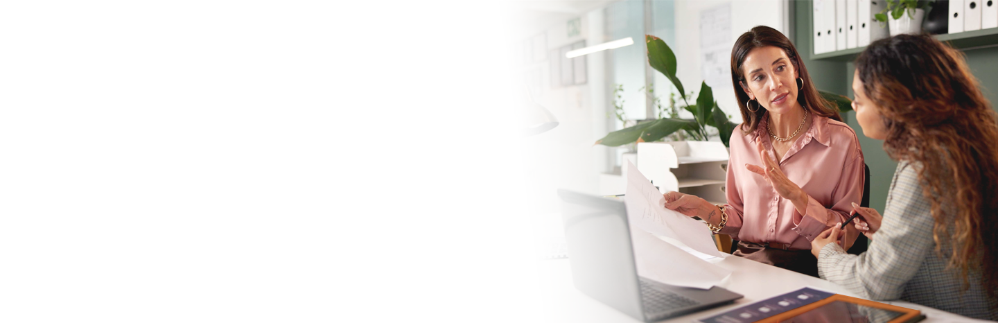 Middle-aged woman is advising a younger woman in an office