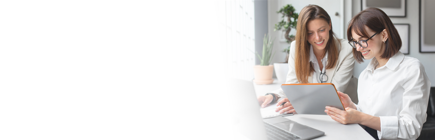 Two professional women in an office working together on a tablet