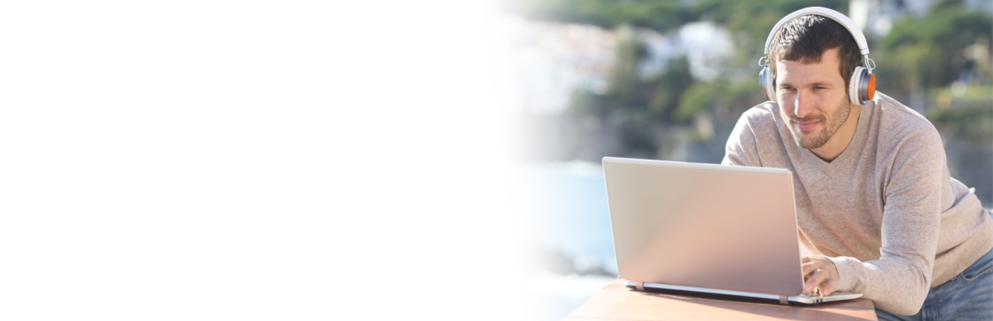 Serious man with headphones uses a laptop in a balcony