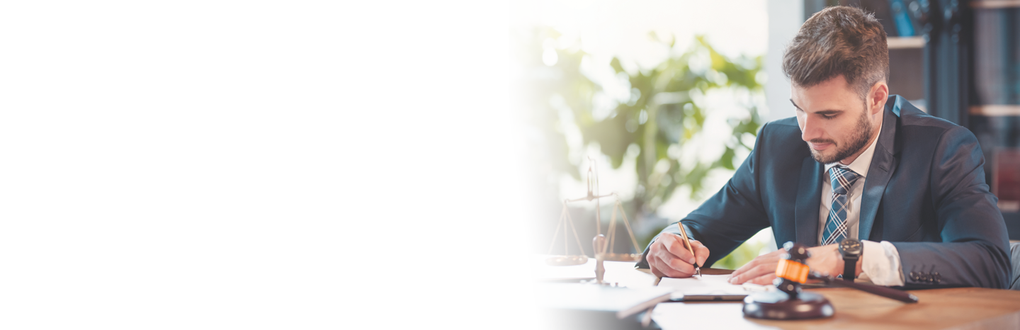 Young man lawyer writing notes at his desk with a gavel and scales of justice