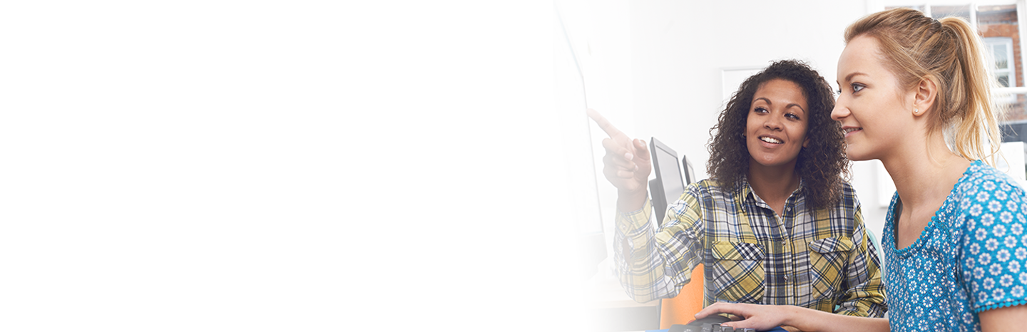 Young women helping each other on a computer