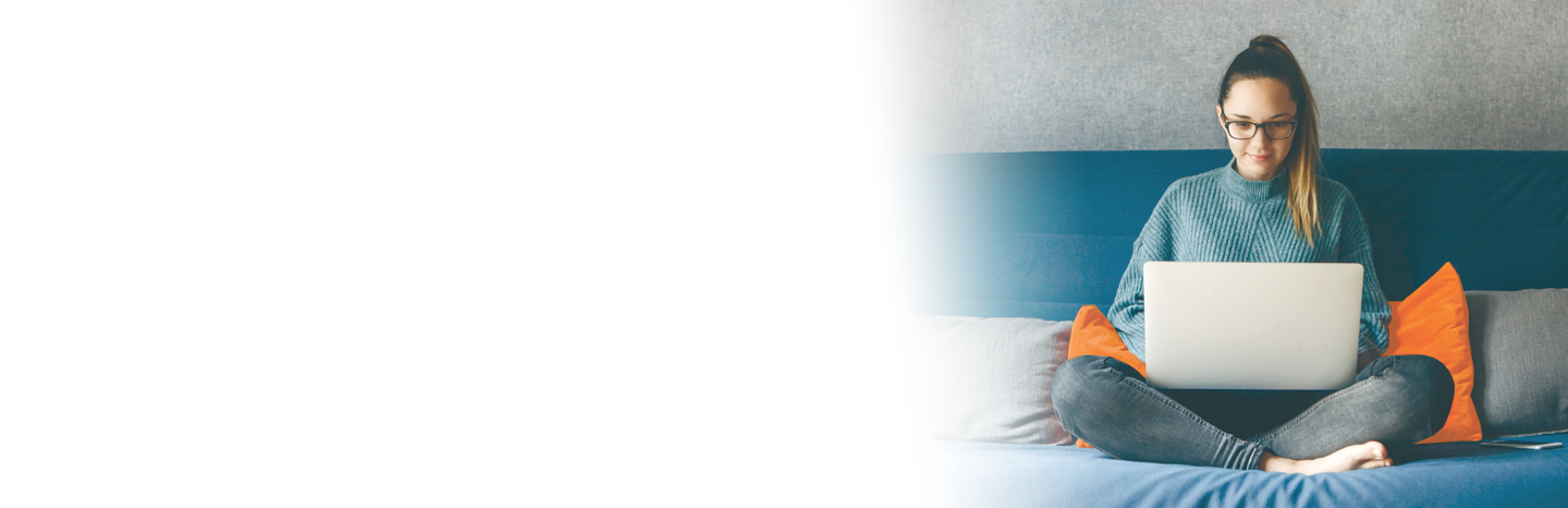 A young woman working on her laptop at home on her bed