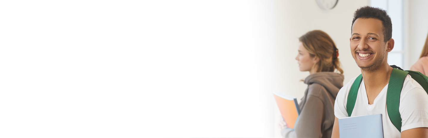 A smiling young man with a green backpack in class