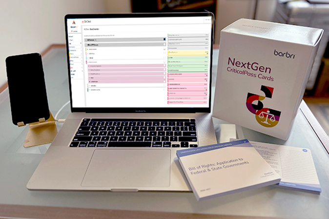 Desk with a mobile device, laptop chosing digital critical pass card with the actual set of NextGen cards sitting next to it