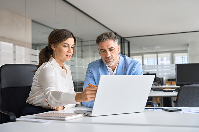 Professional man and woman discussing something in an office on a laptop