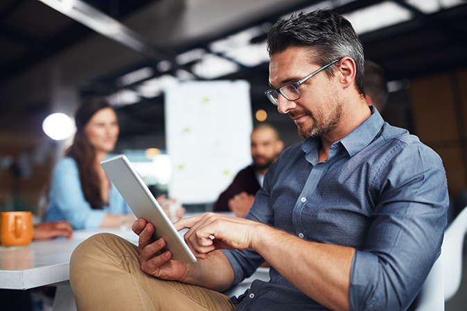 Middle-aged man sitting in an office conference room using a tablet