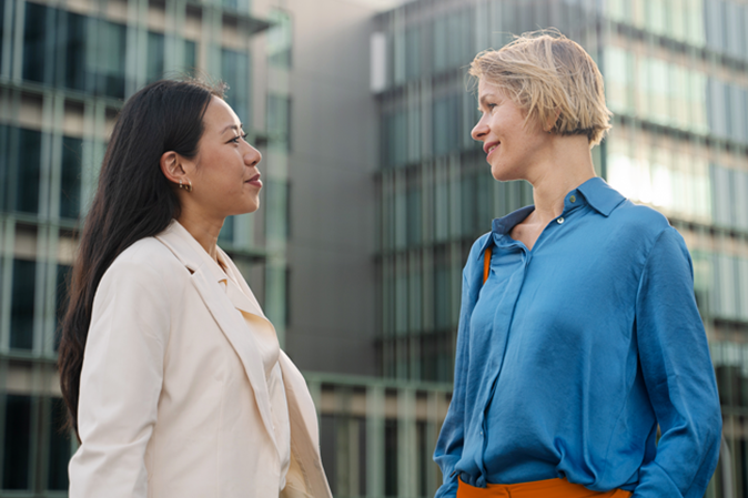 Business women talking outdoors the workplace, Caucasian and Asian female coworkers in the city