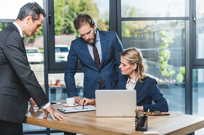 Three lawyers working together in front of a laptop in an office
