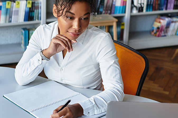 Young woman learning on computer taking notes