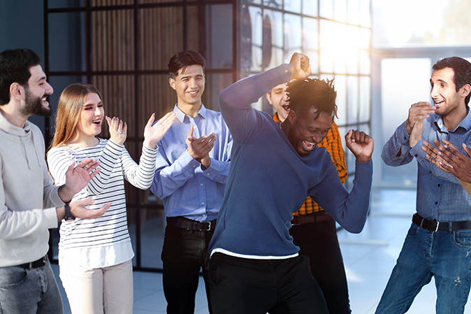 Young man dancing and celebrating surrounded by his friends